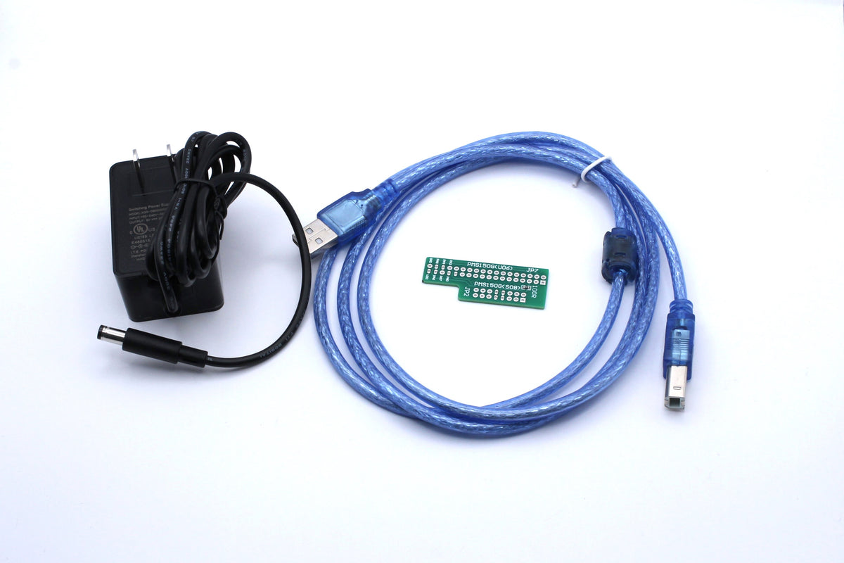 Black power adapter, blue USB cable and green adapter PCB photographed for the PADAUK programmer